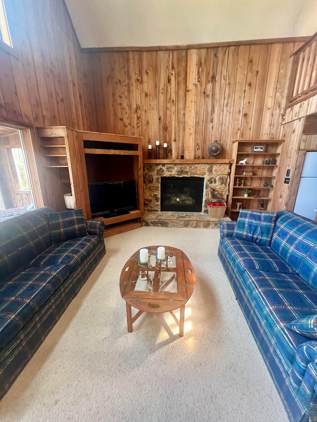 carpeted living area featuring a stone fireplace, built in features, and wood walls