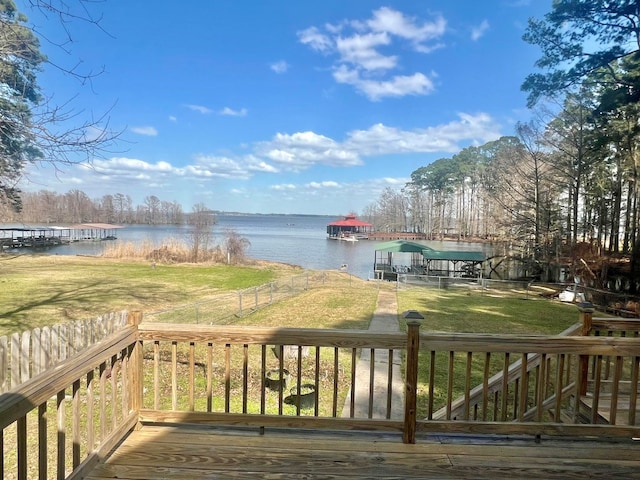 wooden deck featuring a yard, fence, a water view, and a boat dock