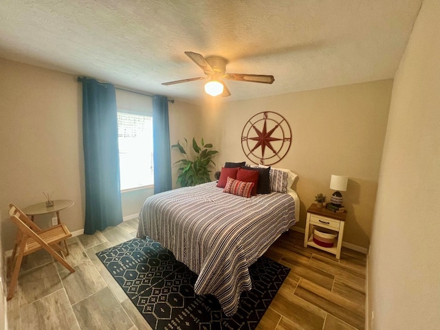 bedroom with baseboards, a textured ceiling, a ceiling fan, and wood tiled floor