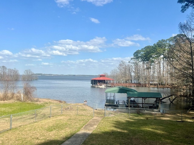 dock area featuring a yard, a water view, boat lift, and fence