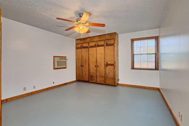 unfurnished bedroom with a textured ceiling, ceiling fan, and a wall mounted air conditioner