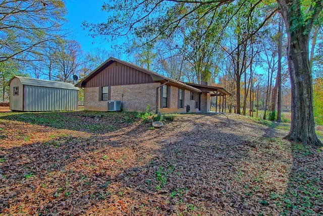 view of side of property featuring central AC and a storage shed