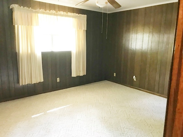 spare room featuring carpet, wood walls, and a ceiling fan