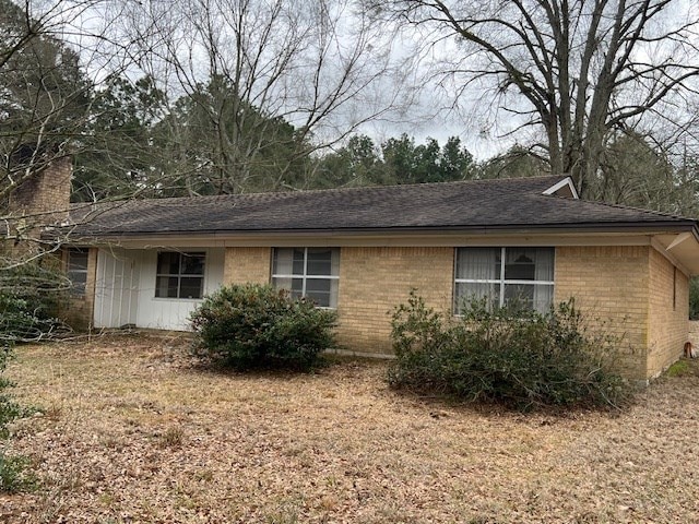 view of home's exterior with brick siding and roof with shingles