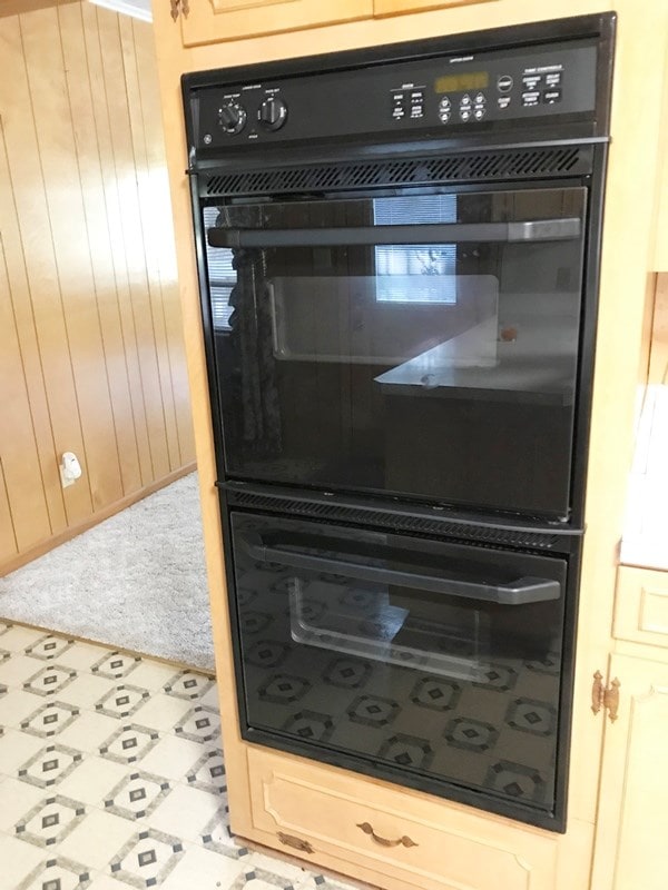 details featuring tile patterned floors, wooden walls, carpet flooring, and dobule oven black