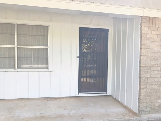 entrance to property featuring board and batten siding and brick siding