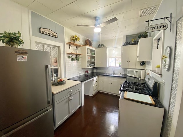 kitchen with backsplash, white cabinets, sink, stainless steel fridge, and range with gas stovetop