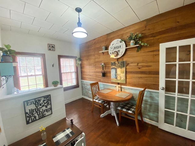 dining space with dark hardwood / wood-style floors and wooden walls