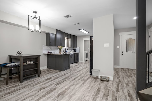 kitchen featuring pendant lighting, light hardwood / wood-style flooring, tasteful backsplash, a notable chandelier, and light stone countertops