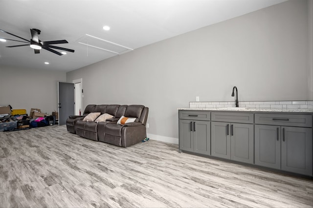 living room featuring sink, ceiling fan, and light wood-type flooring