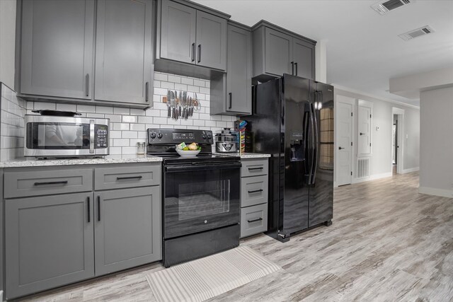 kitchen featuring gray cabinetry, backsplash, black appliances, and light hardwood / wood-style floors