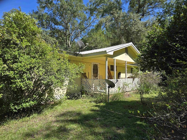 view of side of property featuring covered porch and a yard