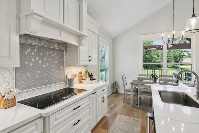 kitchen with pendant lighting, lofted ceiling, backsplash, sink, and white cabinetry