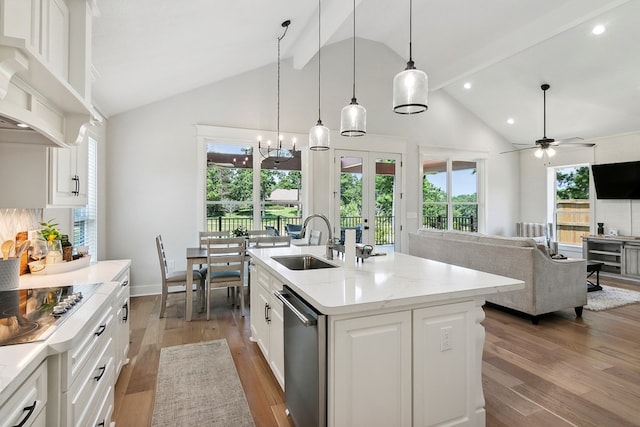 kitchen with stainless steel dishwasher, ceiling fan with notable chandelier, sink, a center island with sink, and white cabinetry