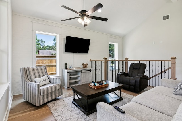 living room featuring ceiling fan, light wood-type flooring, and vaulted ceiling