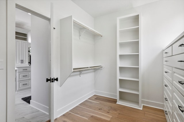 walk in closet with light hardwood / wood-style floors