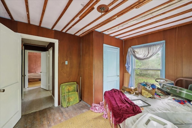 bedroom with beamed ceiling, wooden walls, and wood-type flooring