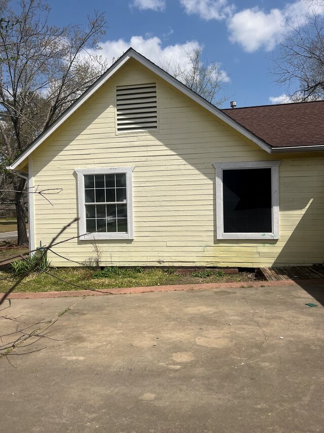 view of home's exterior featuring a shingled roof and a patio area