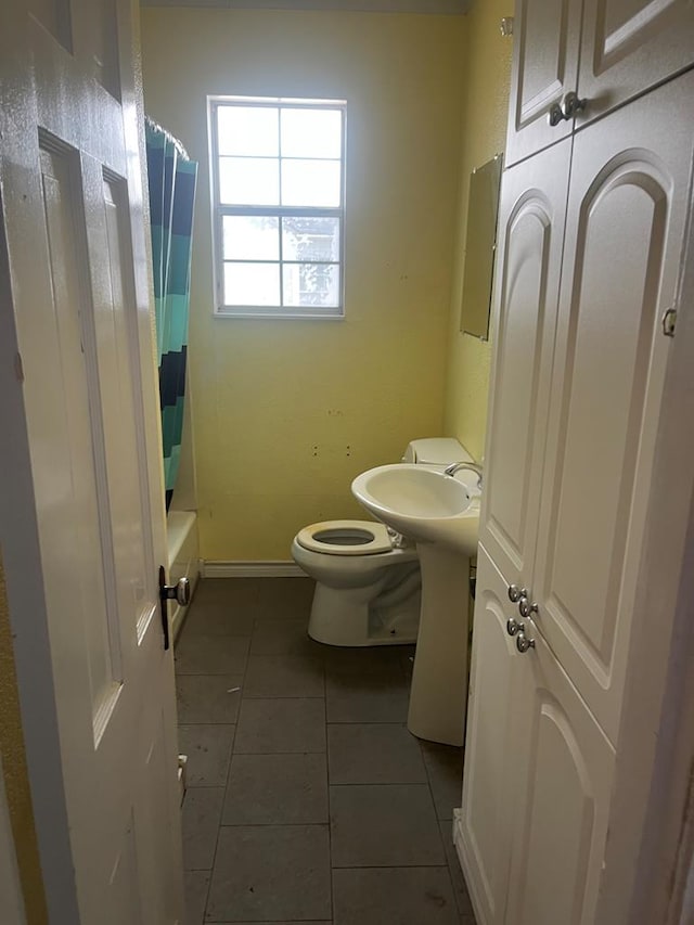 full bath with baseboards, tile patterned floors, and toilet