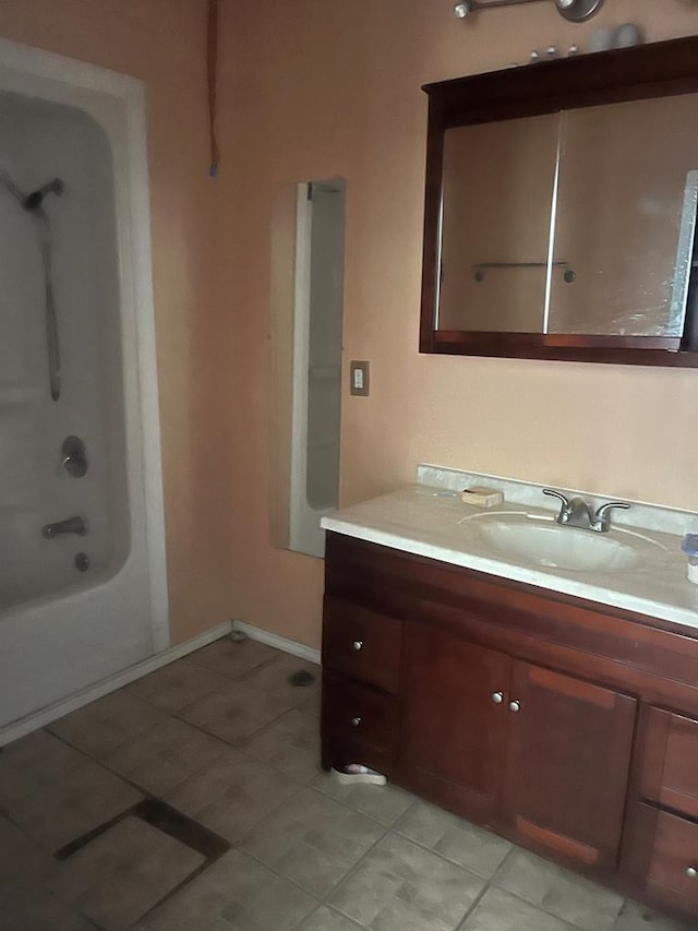 bathroom featuring tile patterned floors, baseboards, shower / bathing tub combination, and vanity