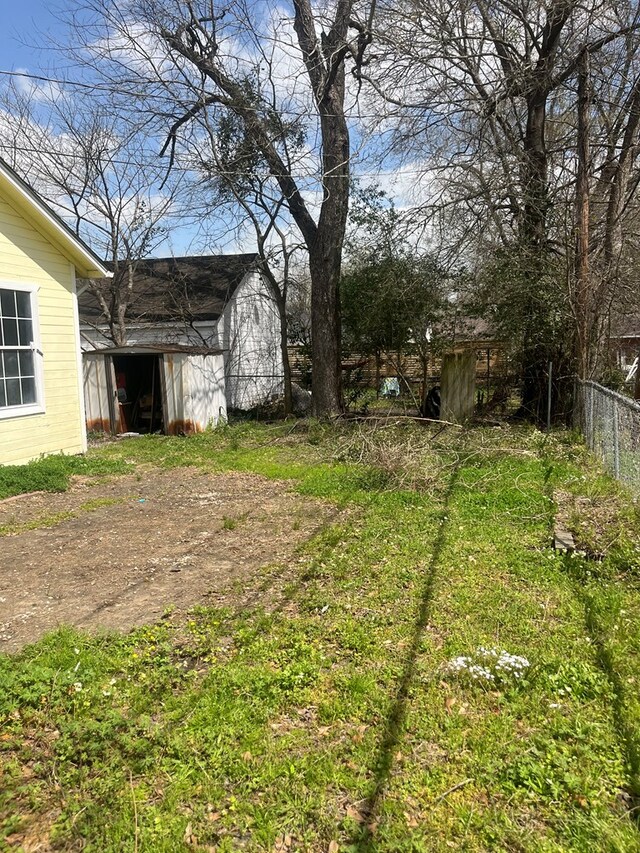 view of yard with a storage shed, fence, and an outdoor structure