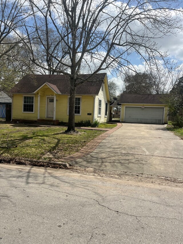 view of front of home with an attached garage, an outbuilding, a front lawn, and driveway