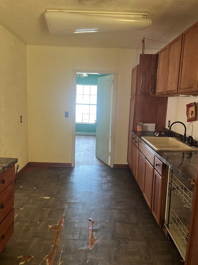 kitchen featuring a sink, dark countertops, baseboards, and brown cabinets