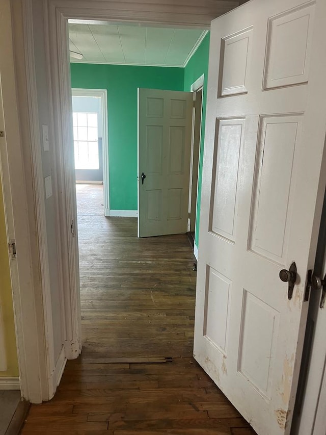 hall featuring crown molding, baseboards, and dark wood finished floors