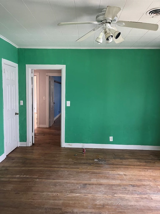 unfurnished room with crown molding, ceiling fan, baseboards, wood finished floors, and visible vents