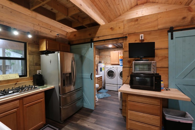 kitchen featuring a barn door, washing machine and clothes dryer, stainless steel appliances, and wood walls