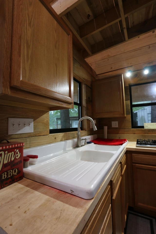 kitchen featuring stainless steel gas stovetop, wooden walls, wooden counters, and a sink