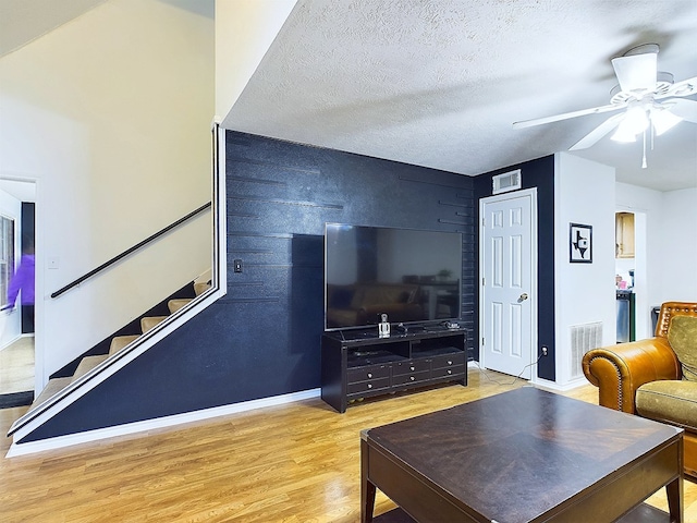 living room featuring a textured ceiling, light hardwood / wood-style flooring, and ceiling fan