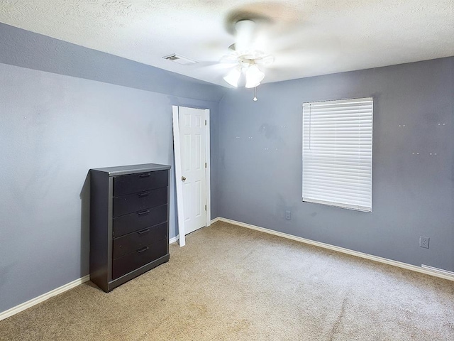 unfurnished bedroom with ceiling fan, light colored carpet, and a textured ceiling