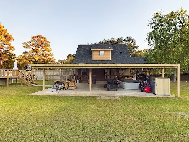 back of house featuring a patio, a hot tub, a wooden deck, and a lawn