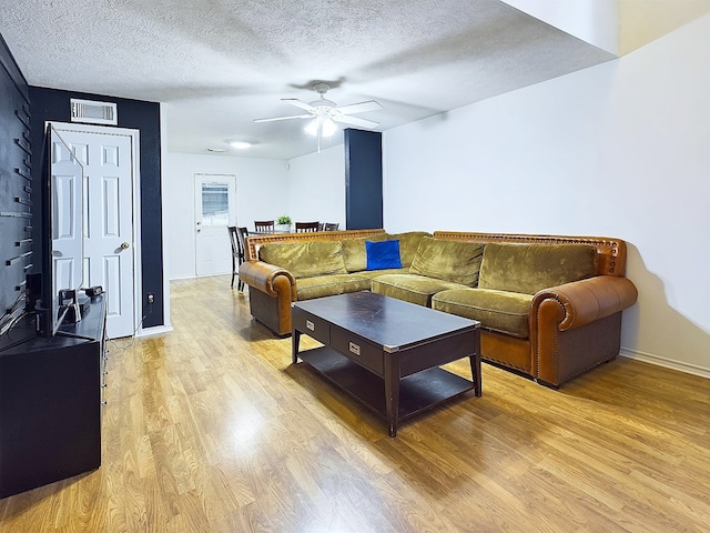 living room with ceiling fan, light hardwood / wood-style floors, and a textured ceiling