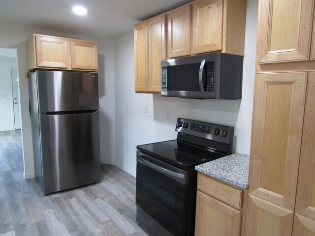 409 W 4th St, Hereford, TX 79045 - kitchen featuring light stone countertops, light brown cabinetry, stainless steel appliances, and light wood-type flooring