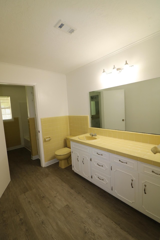 bathroom featuring hardwood / wood-style floors, vanity, tile walls, and ornamental molding