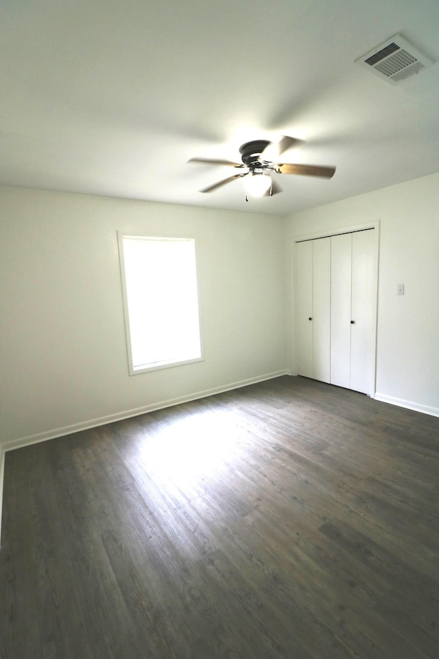 unfurnished bedroom with ceiling fan, dark hardwood / wood-style flooring, and a closet