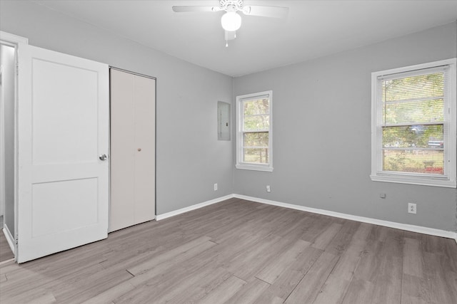 unfurnished bedroom featuring ceiling fan, electric panel, light wood-type flooring, and a closet