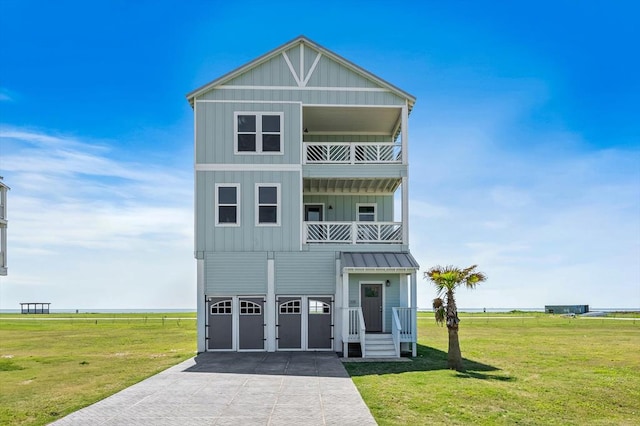 beach home featuring board and batten siding, concrete driveway, a front lawn, and a balcony