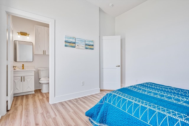 bedroom with light wood-type flooring, baseboards, and ensuite bath