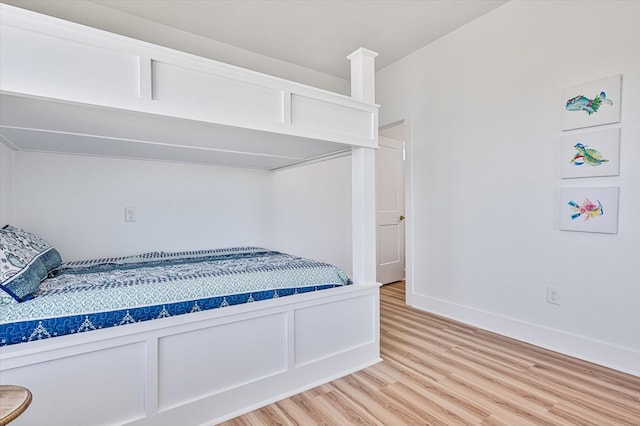 bedroom with baseboards, wainscoting, and light wood-style floors
