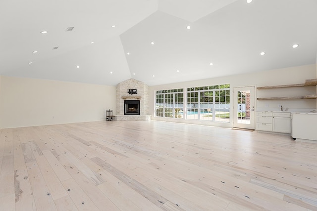 unfurnished living room featuring light wood-type flooring, lofted ceiling, and sink