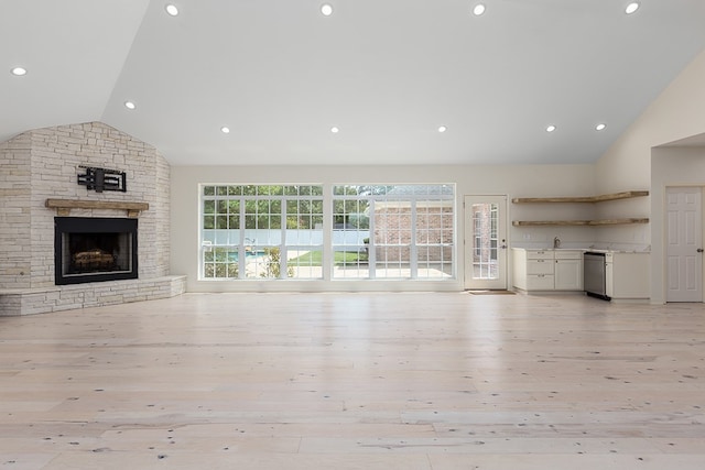 unfurnished living room with a stone fireplace, light hardwood / wood-style flooring, and high vaulted ceiling