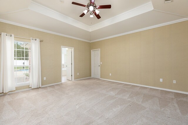 empty room featuring light carpet, a tray ceiling, ceiling fan, and crown molding