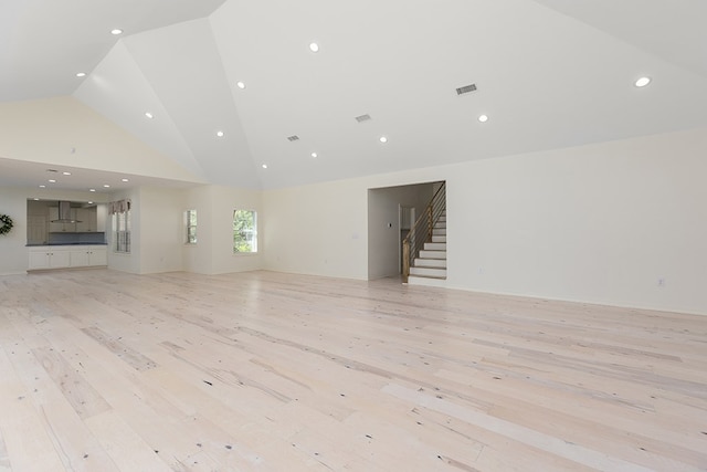 unfurnished living room with high vaulted ceiling and light hardwood / wood-style flooring