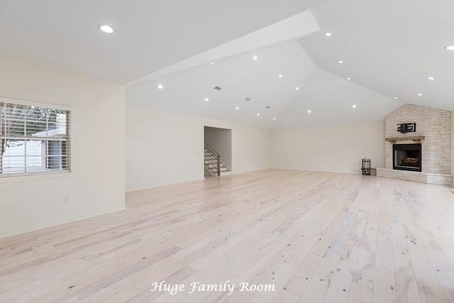 unfurnished living room with light hardwood / wood-style floors, vaulted ceiling, and a stone fireplace