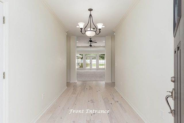 hallway with french doors, light wood-type flooring, crown molding, and an inviting chandelier