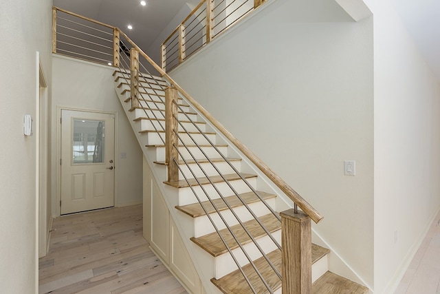 staircase with hardwood / wood-style flooring and a high ceiling