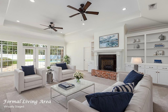 carpeted living room featuring ceiling fan, crown molding, a fireplace, and french doors